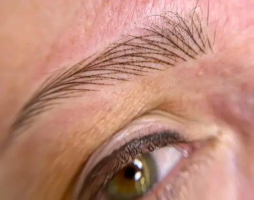 micropigmentacion Primer plano de la ceja y el ojo de una persona, con micropigmentación detallada con trazos individuales que imitan el cabello. El ojo verde mira ligeramente hacia arriba, realzando el aspecto natural de la técnica de microblading. Monica Aranguez